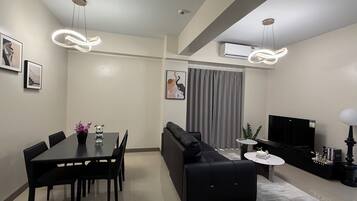 A modern living room with a dining area, a sofa, a TV, and a fireplace.