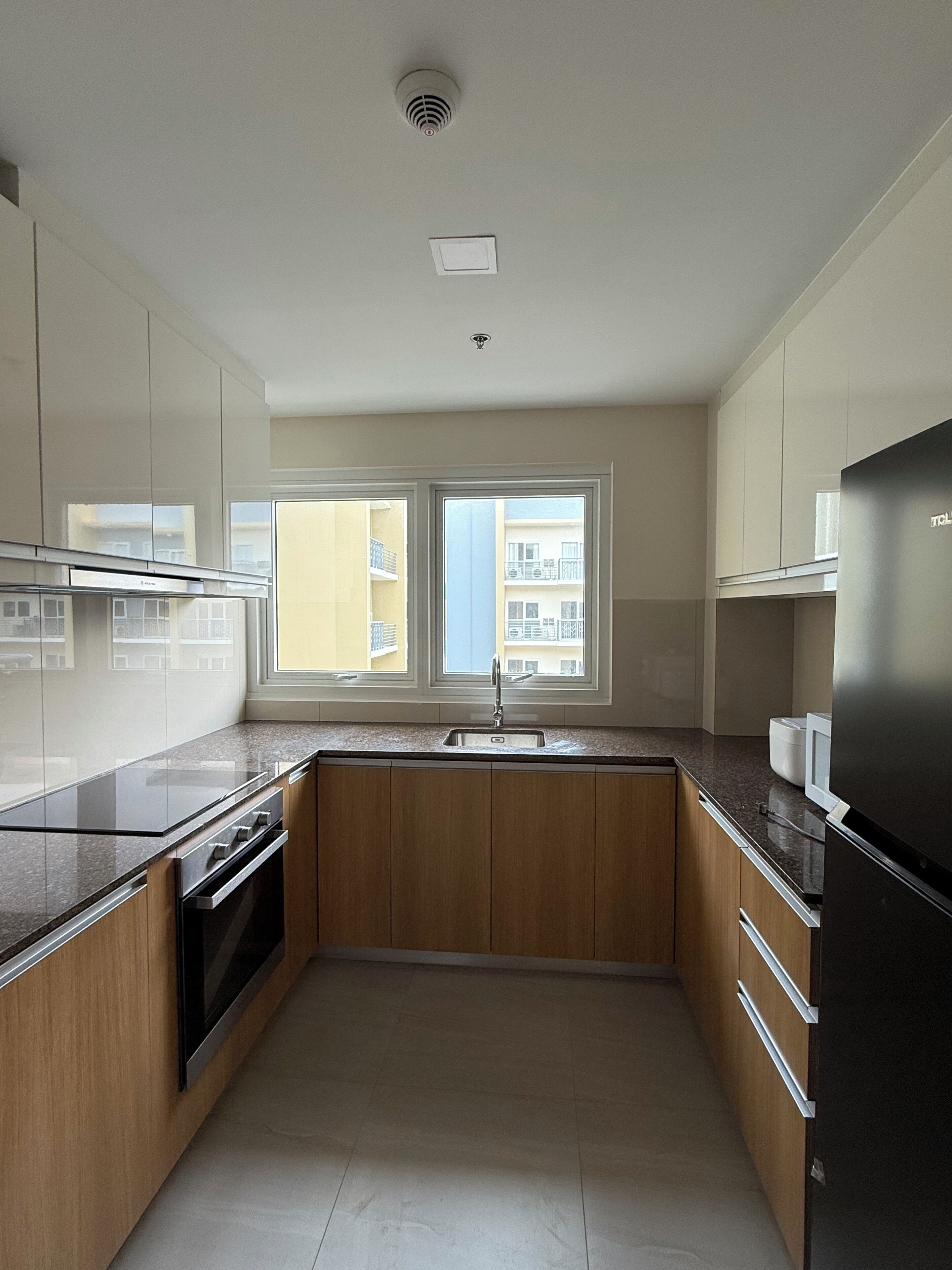 A kitchen with a window, stainless steel appliances, and wooden cabinets.