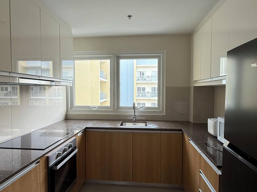 A kitchen with a window, stainless steel appliances, and wooden cabinets.