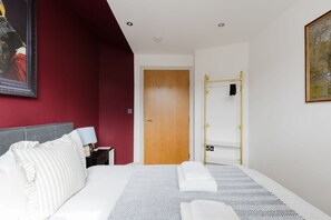 Ein Hotelzimmer mit einem Bett, einem Nachttisch, einer Lampe, einem Kleiderschrank und einer Tür.