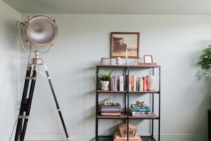 A room with a tripod-mounted light, a bookshelf with books and decorative items, and a framed picture on the wall. - GuestReady - Gated West London Retreat (NO WIFI) (London)