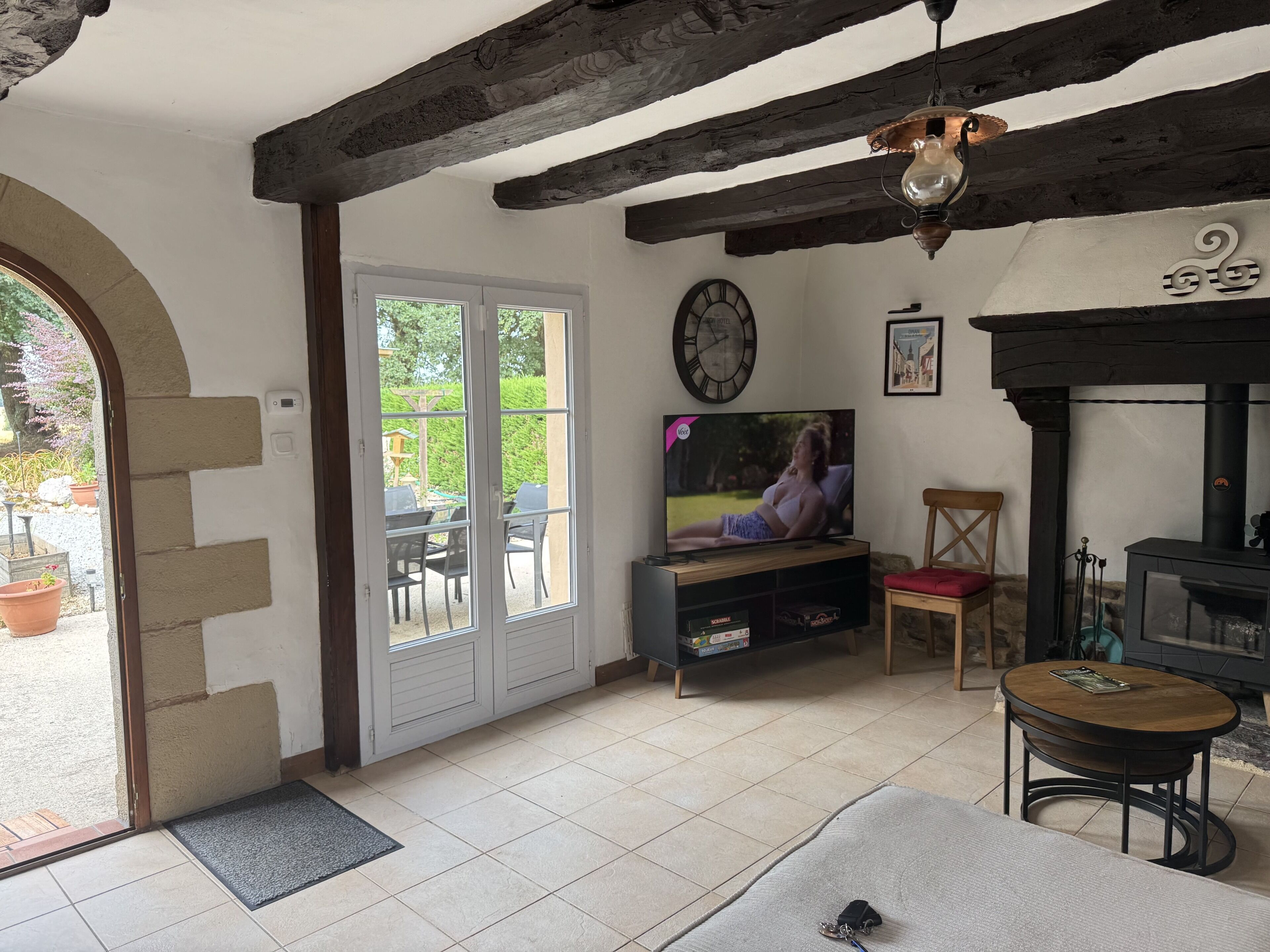 Una sala de estar con televisor, chimenea y comedor con mobiliario de exterior.