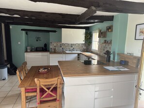 A kitchen with a wooden dining table, white cabinets, and a tiled backsplash. - 84-square-meter house in a quiet location near Brocéliande (Loscouët-sur-Meu)
