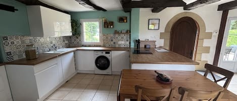 Eine Küche mit Waschmaschine, einem Esstisch und Stühlen sowie einer Holztür.