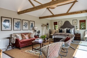 A room with a bed, a sofa, a coffee table, and a chair. There are framed botanical prints on the wall. - Violet Cottage -  Brede , Sussex (Brede)