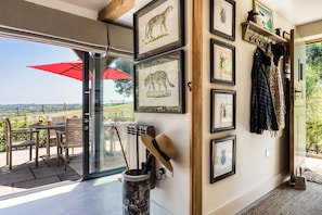 A room with a glass door leading to an outdoor seating area, a fireplace, and a wall decorated with framed animal and insect pictures. - Violet Cottage -  Brede , Sussex (Brede)