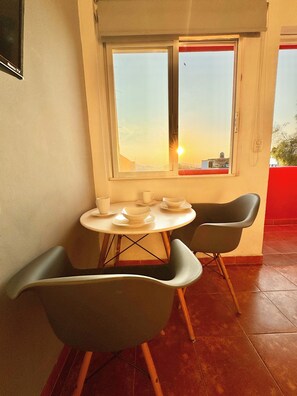 A dining area with a table and chairs, a window with a view, and a red wall. - Sky Flat 2_3___600 mbps fibre optic Wifi__ Great mountain views (Oaxaca de Juárez)