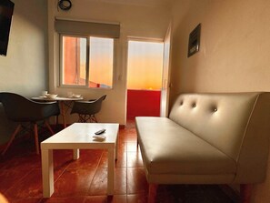 A living room with a sofa, a table, and a chair. There is a window with a view of the sunset. - Sky Flat 2_3___600 mbps fibre optic Wifi__ Great mountain views (Oaxaca de Juárez)