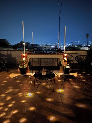 A rooftop terrace with a bench, two potted plants, and a view of the cityscape at night. - Sky Flat 2_3___600 mbps fibre optic Wifi__ Great mountain views (Oaxaca de Juárez)