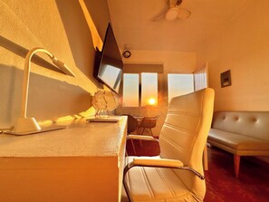 A room with a desk, a chair, a sofa, a television, and a window with a sunset view. - Sky Flat 2_3___600 mbps fibre optic Wifi__ Great mountain views (Oaxaca de Juárez)
