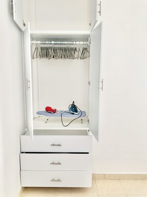 A white wardrobe with open doors, featuring a hanging rack, a flat ironing board, and two drawers. - Sky Flat 2_3___600 mbps fibre optic Wifi__ Great mountain views (Oaxaca de Juárez)