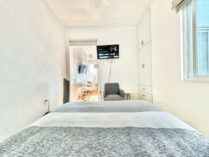 A bedroom with a bed, a desk with a computer, a chair, and a TV mounted on the wall. - Sky Flat 2_3___600 mbps fibre optic Wifi__ Great mountain views (Oaxaca de Juárez)