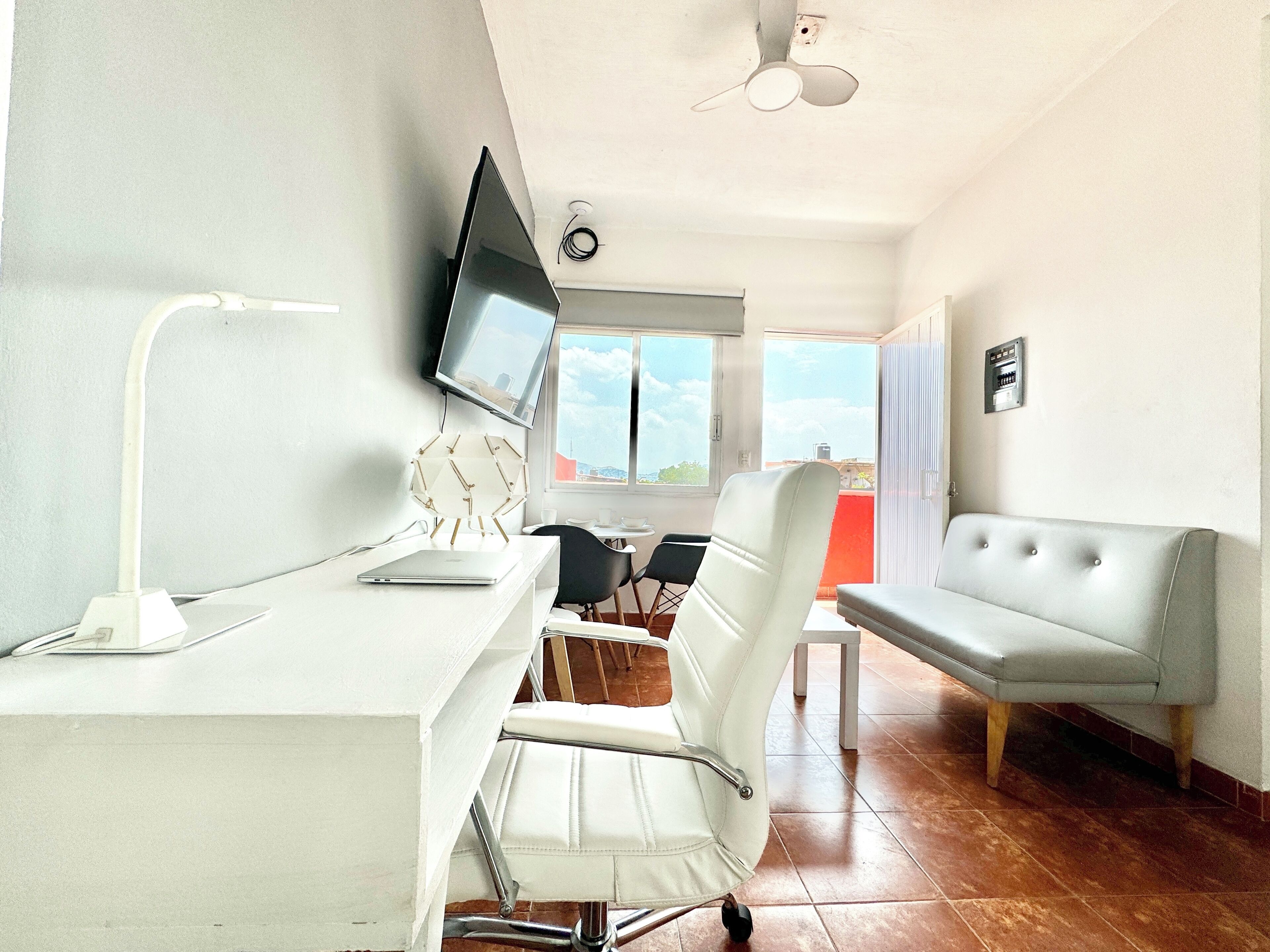 Una habitación con escritorio, silla, televisor y sofá.