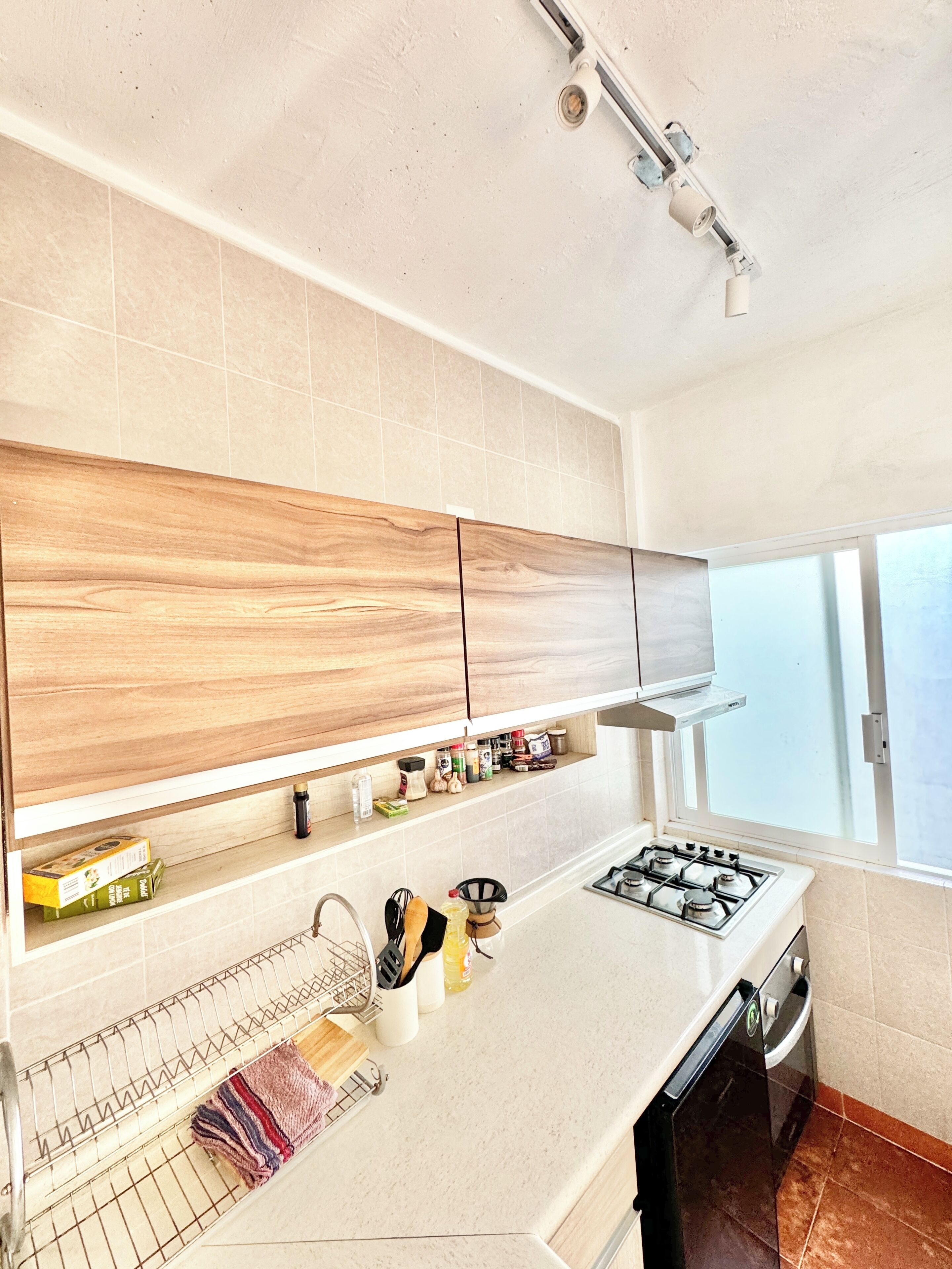 Eine moderne Küche mit Holzausstattung, einem Gasherd und einem Fenster für natürliches Licht.