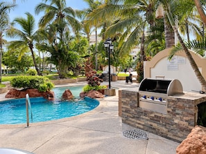 A pool area with a barbecue grill and palm trees. - Costa Bonita Beachfront Family Condo (Mazatlán)