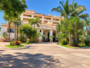 Ein Hotel mit Innenhof, Palmen und einem mehrstöckigen Gebäude mit Balkonen.