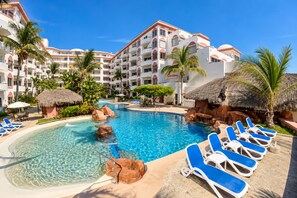 Ein Resortpool mit klarem Wasser, Liegestühlen und Palmen.