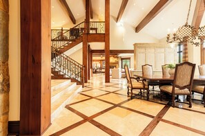 A spacious interior with a grand staircase, a dining area with a large table and chairs, and a fireplace. - Ski-In/Ski-Out 6BR Luxury Estate with Indoor Pool, Hot Tub & Theater at The Colony, Sleeps 26 (Park City)