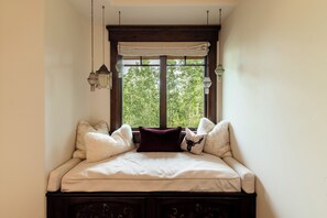A corner bedroom with a large window, a bed with white bedding, and two decorative hanging lamps. - Ski-In/Ski-Out 6BR Luxury Estate with Indoor Pool, Hot Tub & Theater at The Colony, Sleeps 26 (Park City)