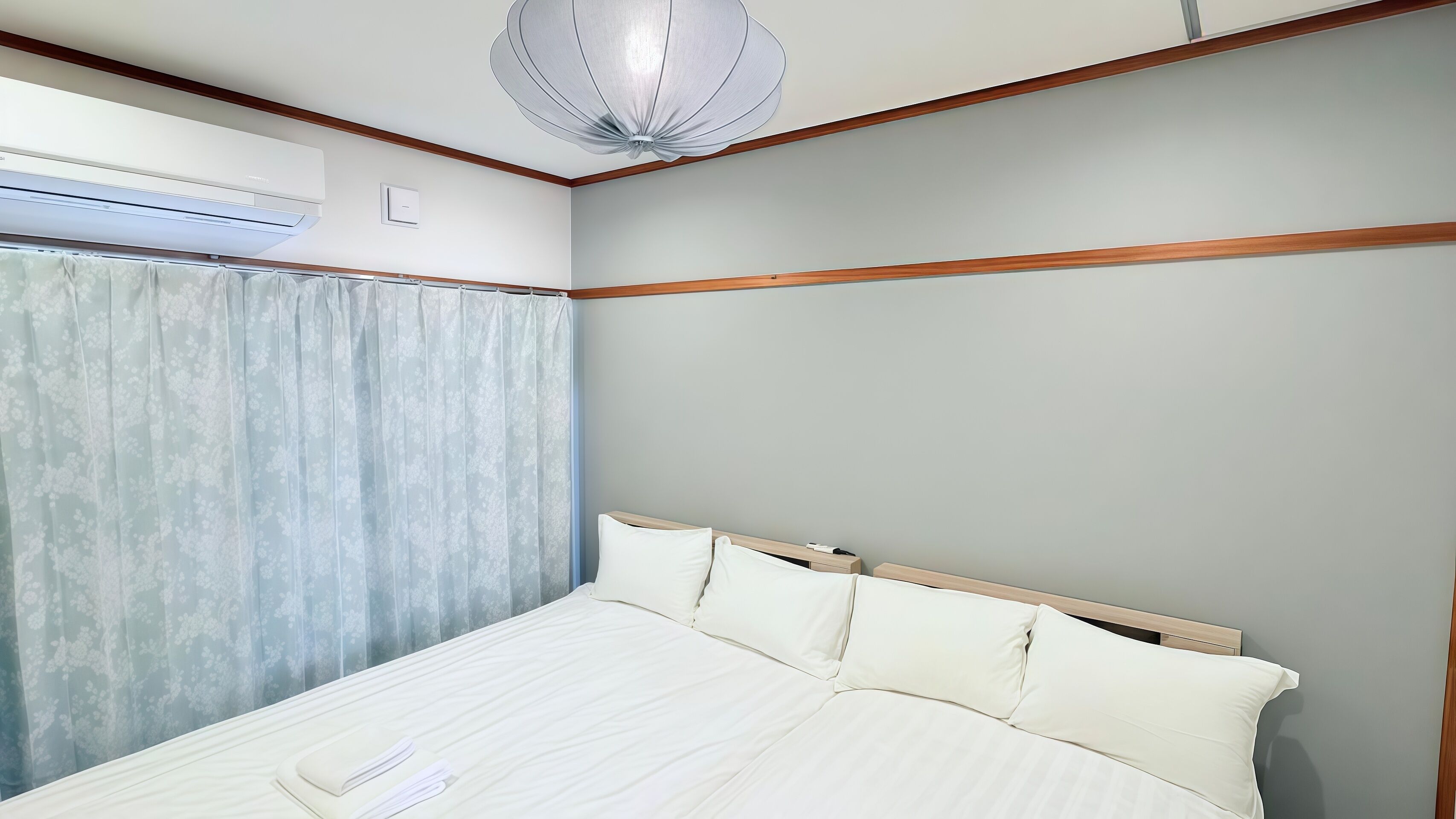 A bedroom with a bed, a ceiling fan, and a window with curtains.