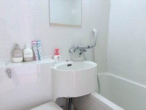 Een badkamer met een wit wastafelmeubel, een spiegel erboven en toiletartikelen op het aanrecht.