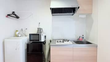 A compact kitchen with a refrigerator, microwave, stove, and sink.