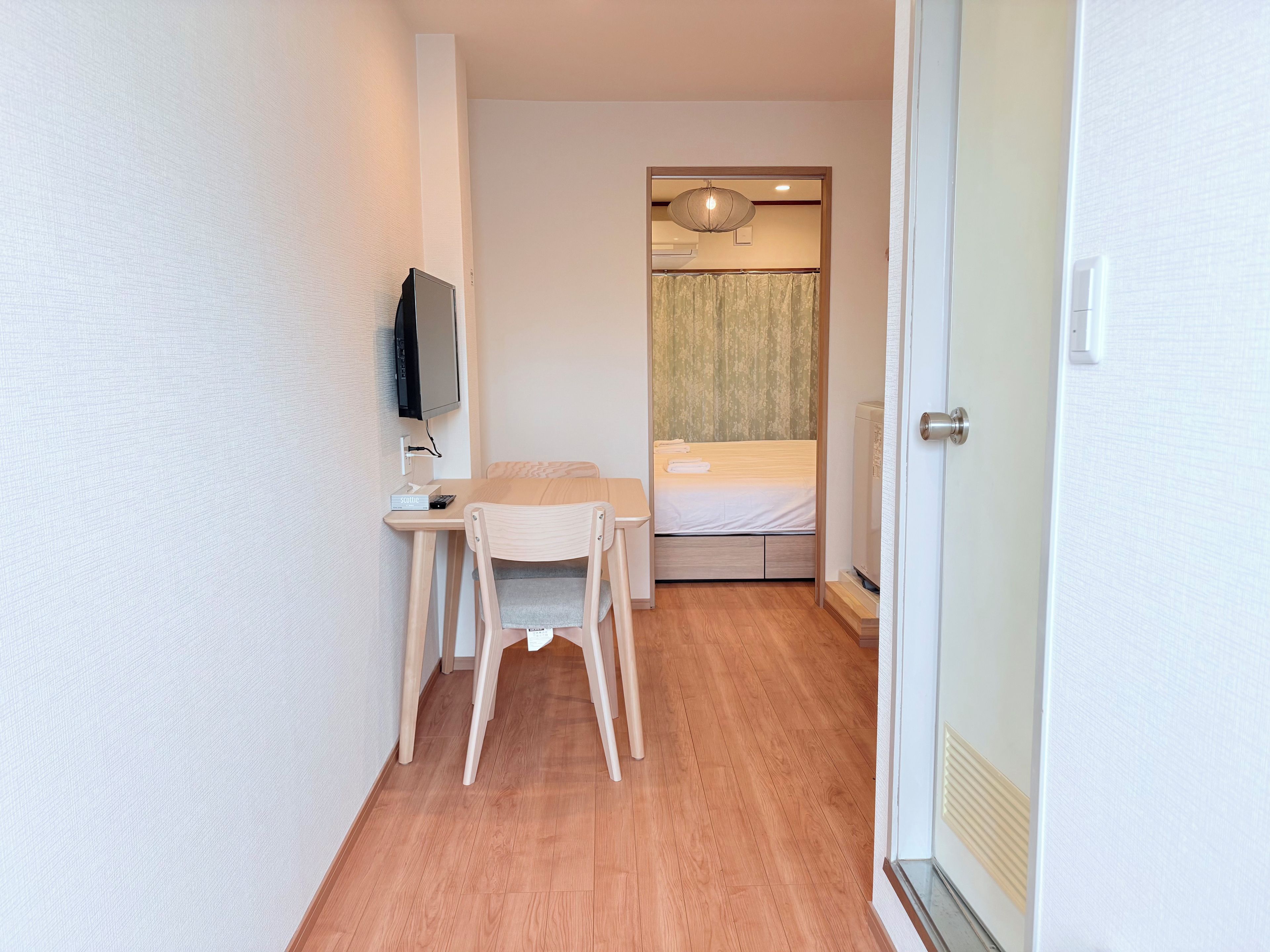 A small, compact room with a bed, a desk, and a chair.