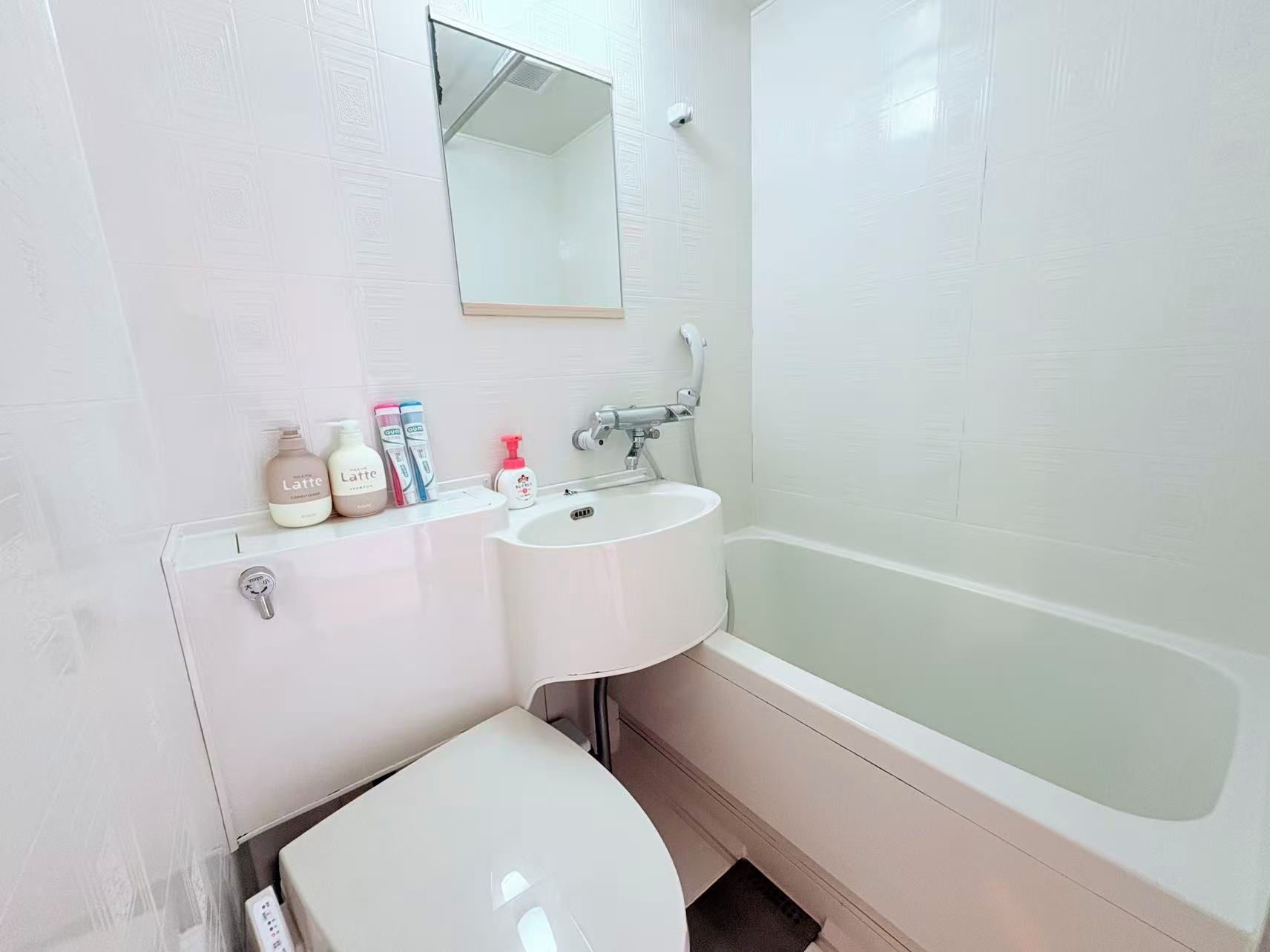 A bathroom with a white sink, a mirror, a toilet, and a bathtub.
