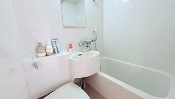 A bathroom with a white sink, a mirror, a toilet, and a bathtub.