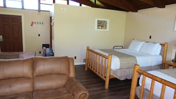 A room with a brown leather sofa, a wooden bed with a headboard, a wooden table, and a framed picture on the wall.