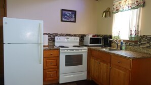 A kitchen with a refrigerator, stove, microwave, and wooden cabinets. - 2 Queen Beds, 1 Bunk Bed, Kitchen, Fireplace (Packwood)