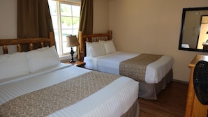 A hotel room with two beds, a wooden headboard, a mirror, and a window with curtains. - 2 Queen Beds, 1 Sofa Bed, Kitchen. No Pets Allowed (Packwood)