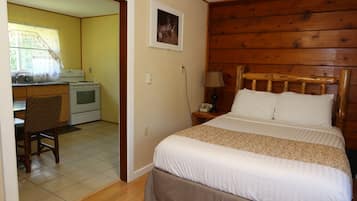 A room with a bed, wooden headboard, a desk with a stove, and a chair.