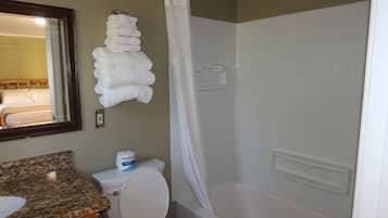 A bathroom with a toilet, a sink, a shower with a curtain, and a towel rack with folded towels.
