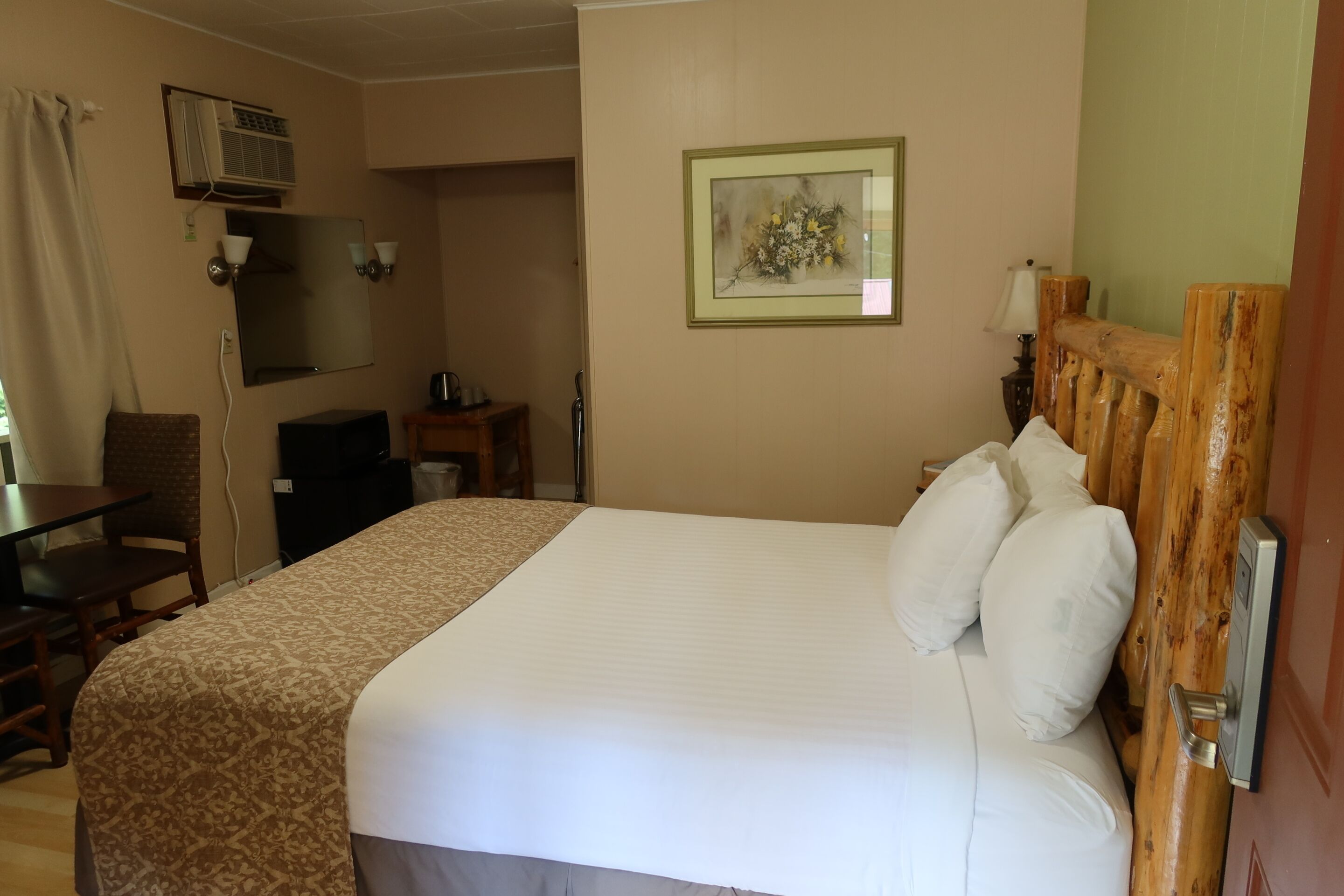 Hotelkamer met een bed, een bureau, een stoel, een klein tafeltje en een lijst met een afbeelding aan de muur.