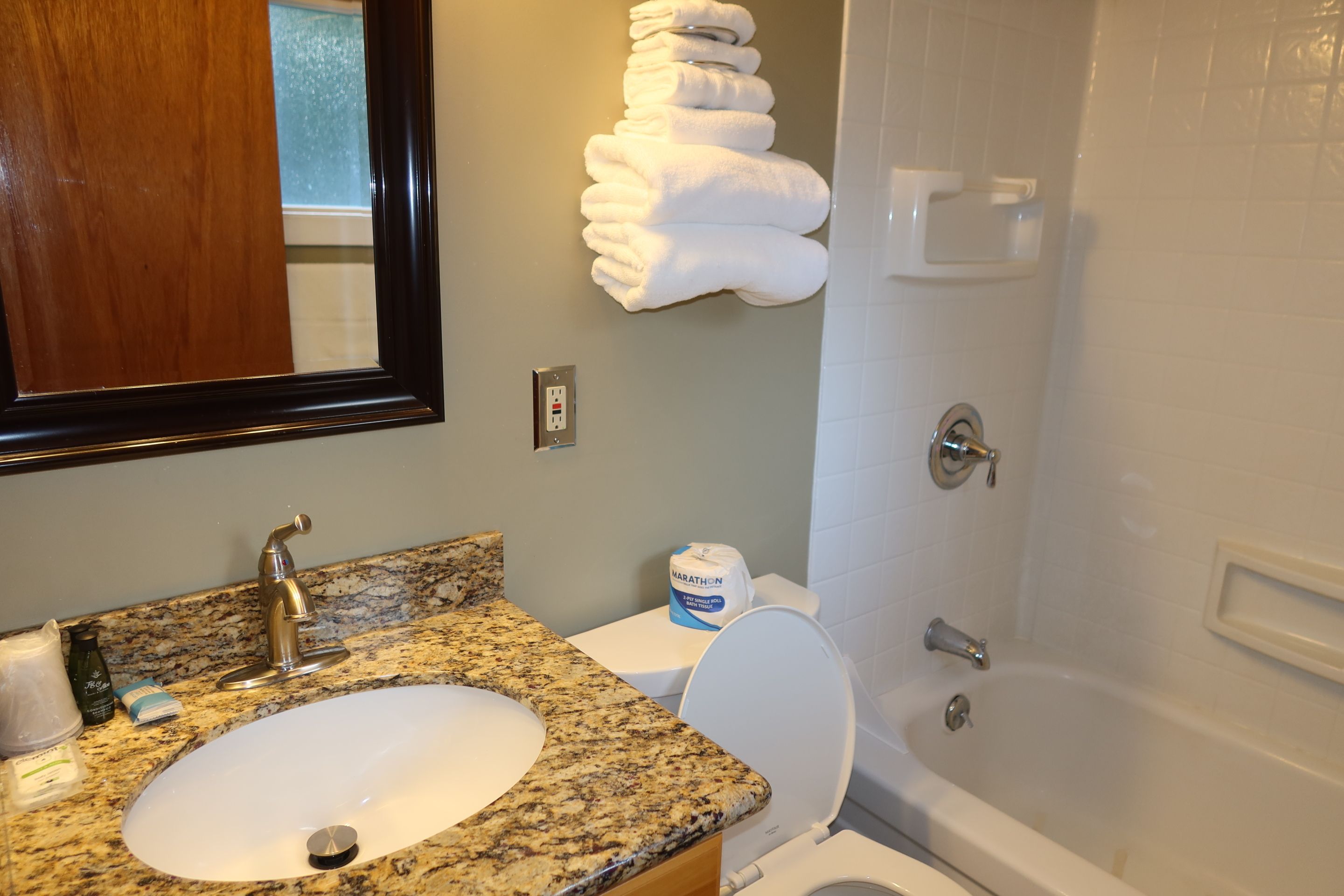 A bathroom with a granite countertop sink, a toilet, and a bathtub.