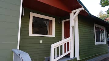 Ein grünes Haus mit weißer Veranda und einer roten Tür.