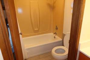 Un baño con bañera, inodoro y cortina de ducha.