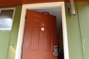 Una puerta roja con el número 14, una ventana a la izquierda y un timbre con luz encima.