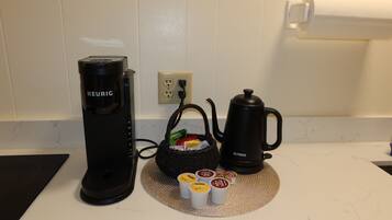 A kitchenette with a Keurig coffee maker, a kettle, and a basket of coffee pods.