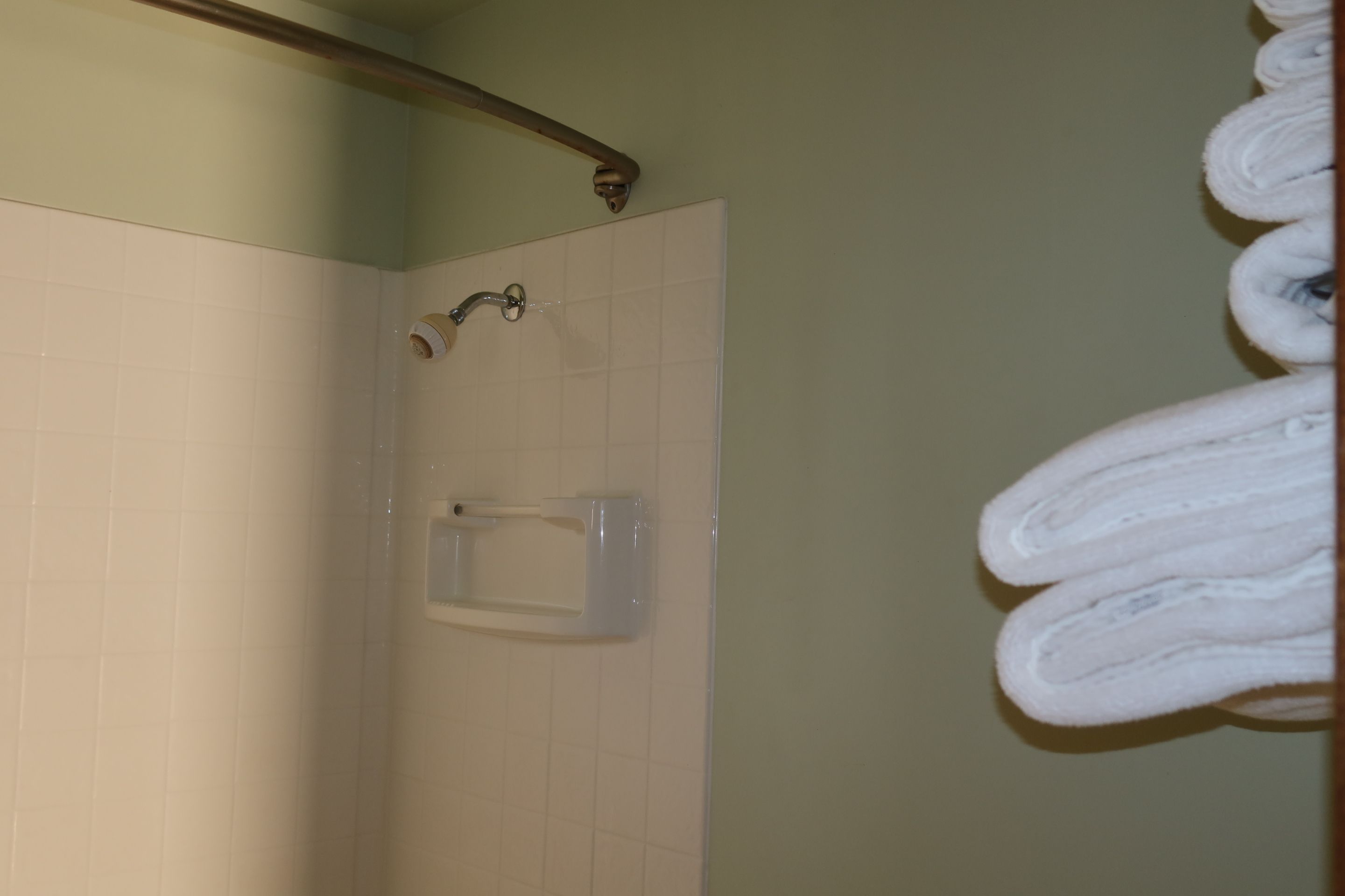 A bathroom with a shower, a towel rack, and a toilet paper holder.