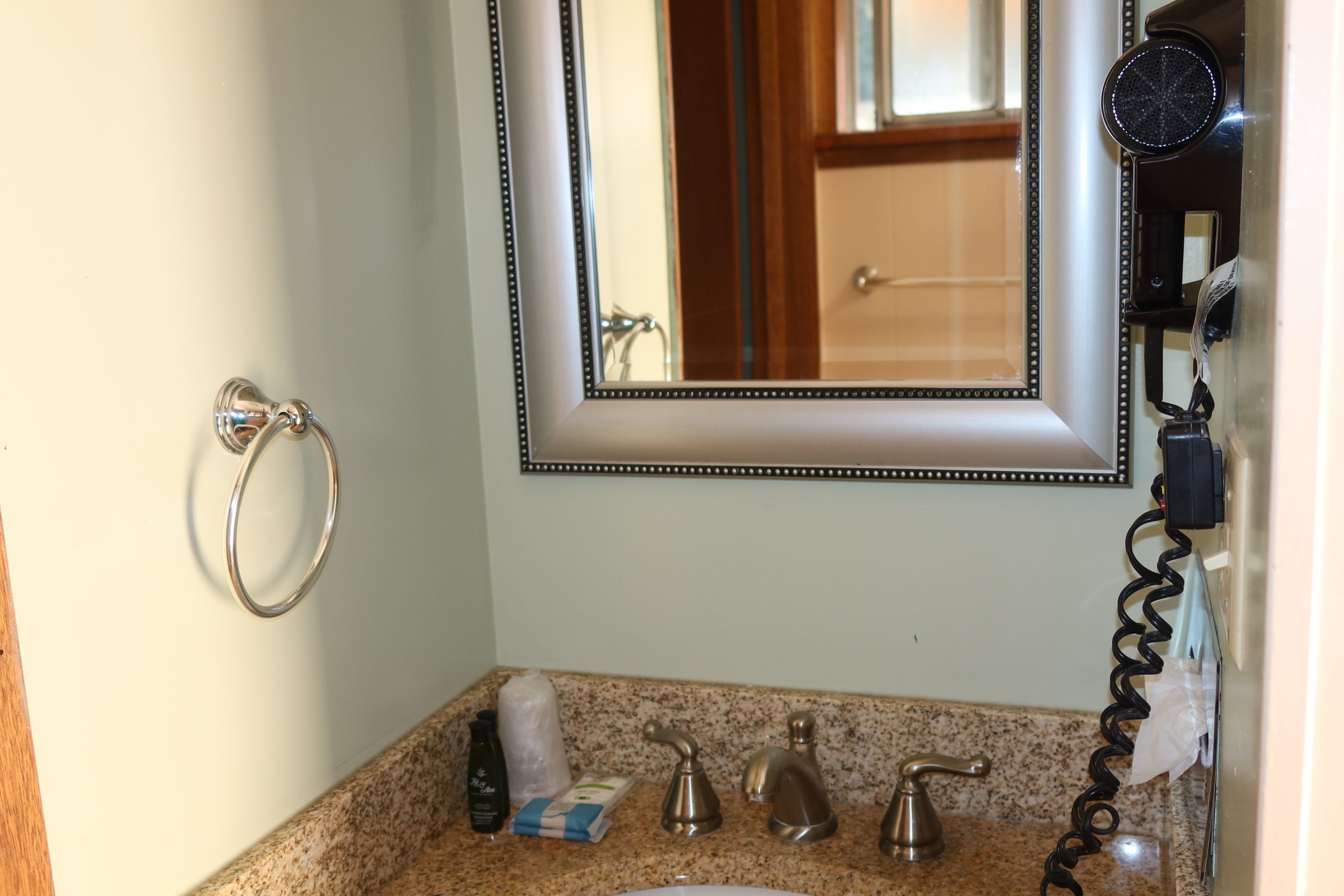 Een badkamer met een wastafel, spiegel, handdoekhouder en een aangesloten haardroger.