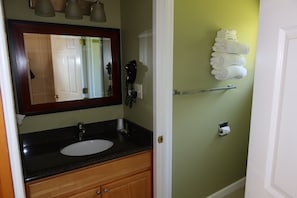 Un baño con lavamanos, espejo, toallero y soporte para papel higiénico.