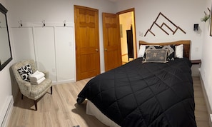 Ein Schlafzimmer mit Bett, Stuhl, Kleiderschrank und Spiegel.