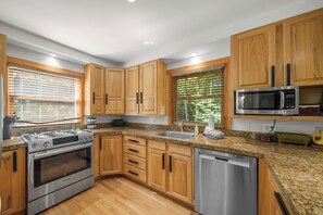 A modern kitchen with wooden cabinets, a Bosch gas range, a stainless steel dishwasher, and a built-in microwave. - The Barking Beech: Pet Friendly, Hot Tub, Firepit, Fenced Yard, 4 TVs! (Banner Elk)