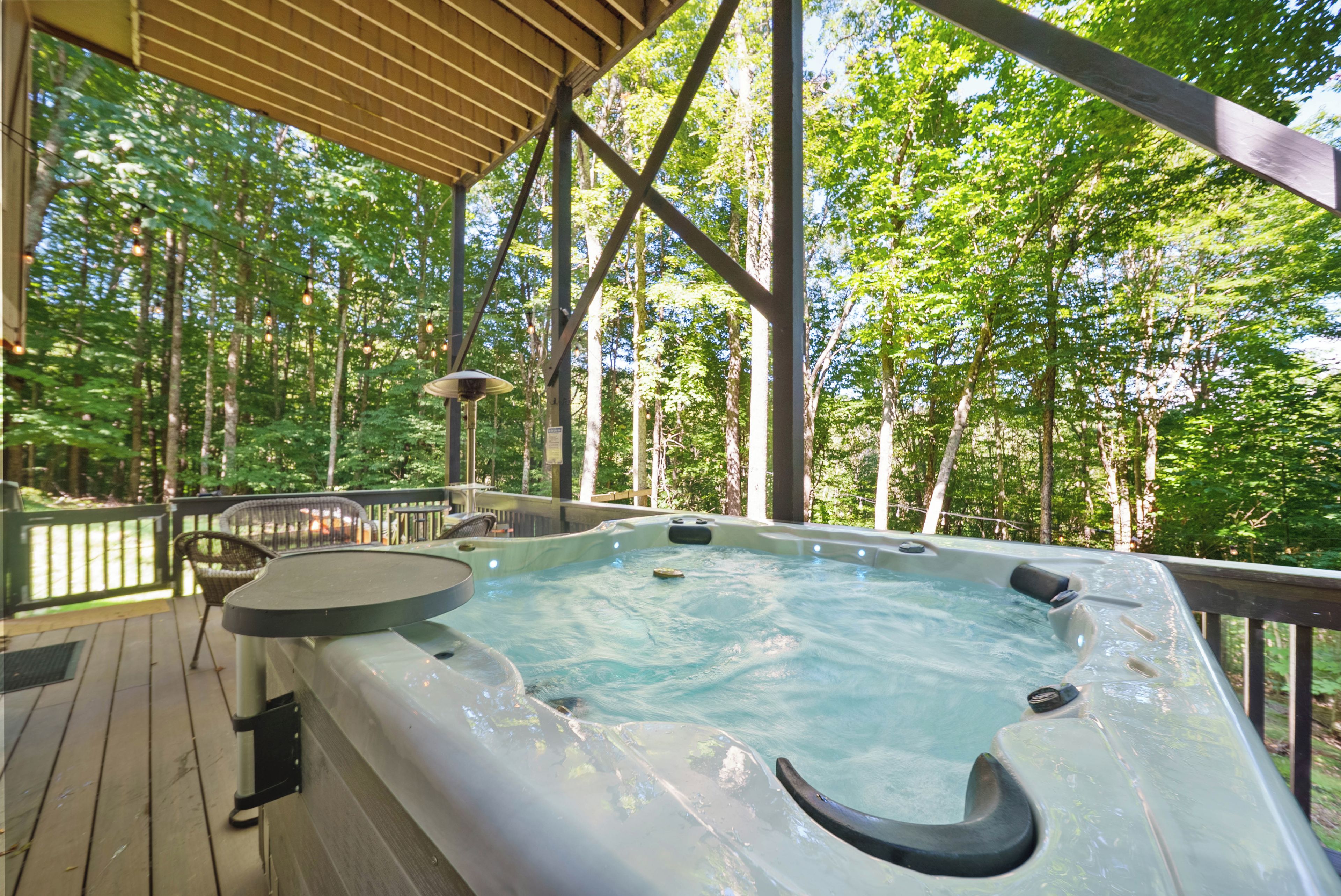 A hot tub on a wooden deck with a view of a forest.