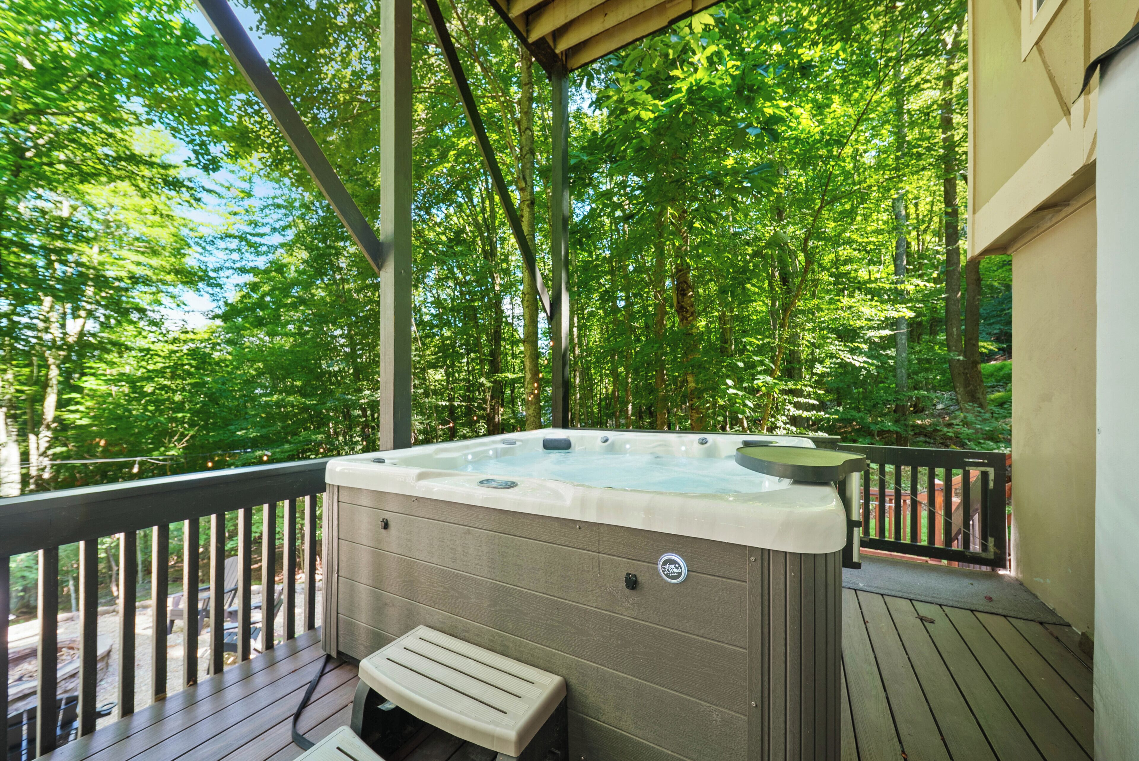A hot tub on a wooden deck with a view of a forest.