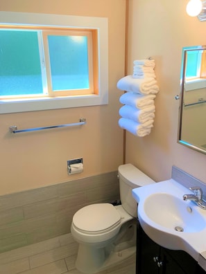 Un baño con inodoro, lavamanos, toallero y ventana.