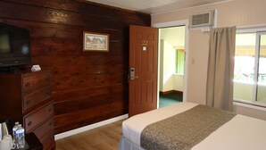 Habitación de hotel con paneles de madera, una cama con una colcha estampada, un aparador con televisor y una puerta con el número 22.