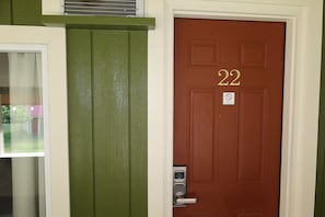 Una puerta marrón con el número 22, un timbre y un letrero de no fumar.